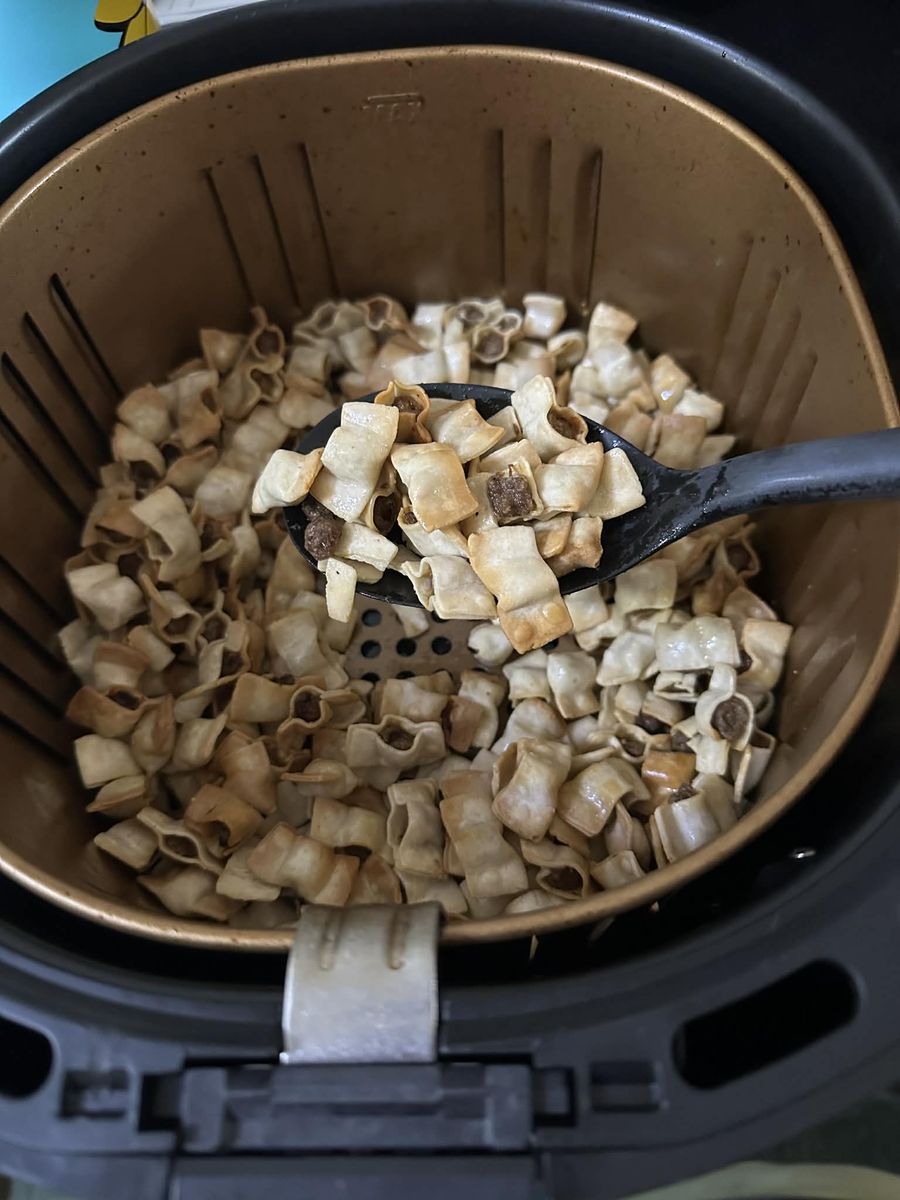 Golden, crispy manti in an air fryer basket with a serving spoon