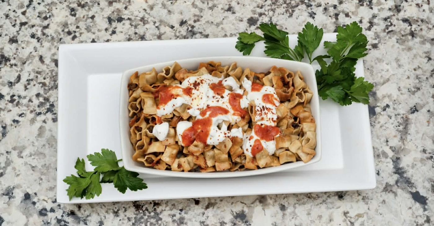Manti in a white rectangular serving dish with parsley